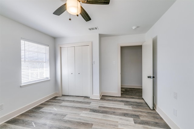 unfurnished bedroom featuring light wood finished floors, a closet, visible vents, ceiling fan, and baseboards