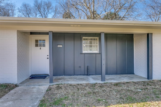 view of exterior entry with board and batten siding and brick siding