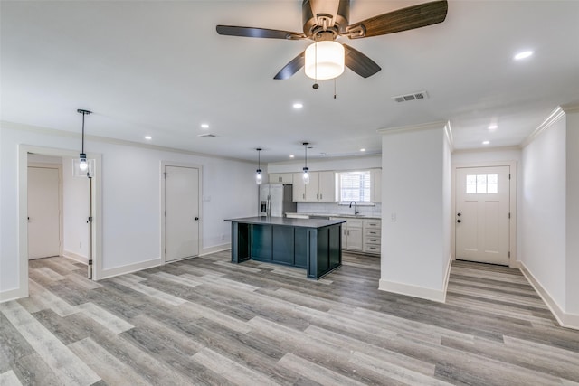 kitchen with hanging light fixtures, a kitchen island, white cabinets, and stainless steel fridge with ice dispenser