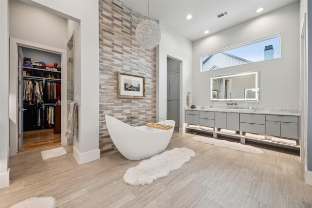 bathroom featuring a freestanding tub, recessed lighting, vanity, visible vents, and a walk in closet