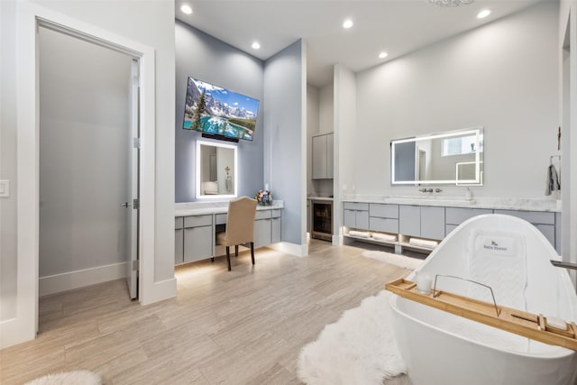 bathroom with beverage cooler, wood finished floors, a freestanding tub, and vanity