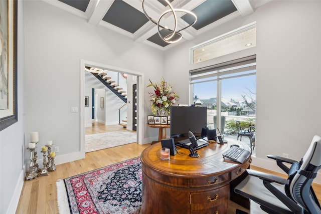 office featuring beam ceiling, wood finished floors, a chandelier, coffered ceiling, and baseboards