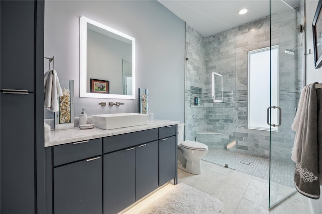 bathroom featuring toilet, tile patterned floors, tiled shower, and vanity