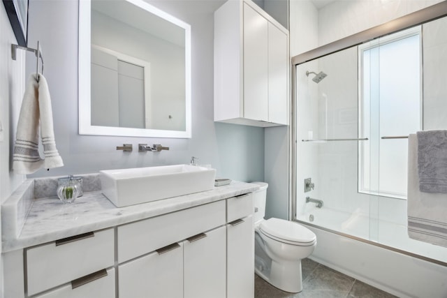 full bath featuring tile patterned flooring, vanity, toilet, and bath / shower combo with glass door