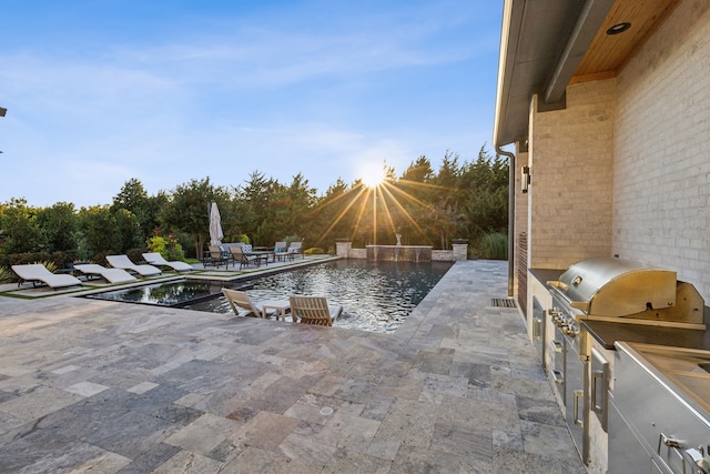 view of patio with grilling area, an outdoor kitchen, and an outdoor pool