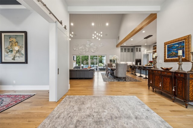 foyer with light wood finished floors, a barn door, a towering ceiling, and baseboards