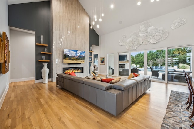 living area with high vaulted ceiling, light wood-type flooring, and a fireplace