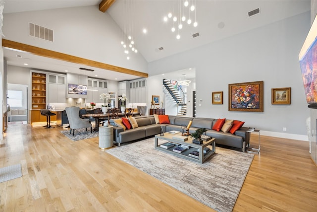 living room featuring stairway, visible vents, and light wood finished floors