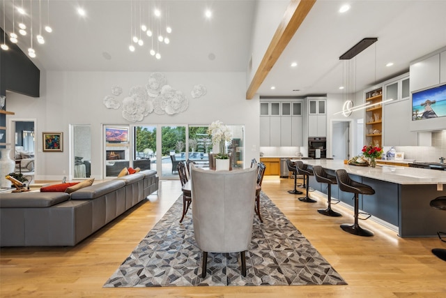 dining space featuring light wood-style floors, a high ceiling, and recessed lighting