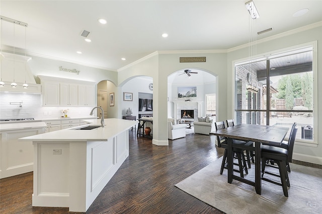 kitchen with a center island with sink, visible vents, white cabinets, light countertops, and a sink