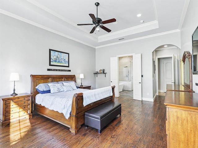 bedroom featuring baseboards, arched walkways, a raised ceiling, ornamental molding, and dark wood-type flooring