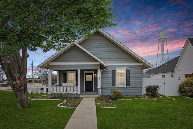 bungalow-style home featuring a front yard, a gate, fence, and covered porch