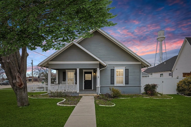 111 S Pine St, Roanoke, TX 76262 - back of property at dusk featuring a shingled roof, an attached garage, covered porch, a lawn, and fence