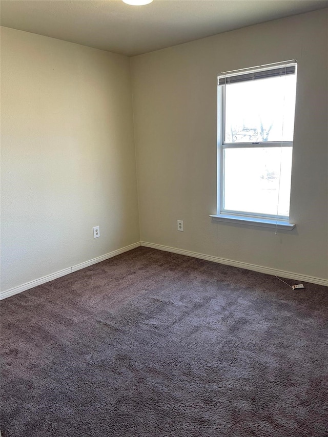 carpeted spare room featuring baseboards