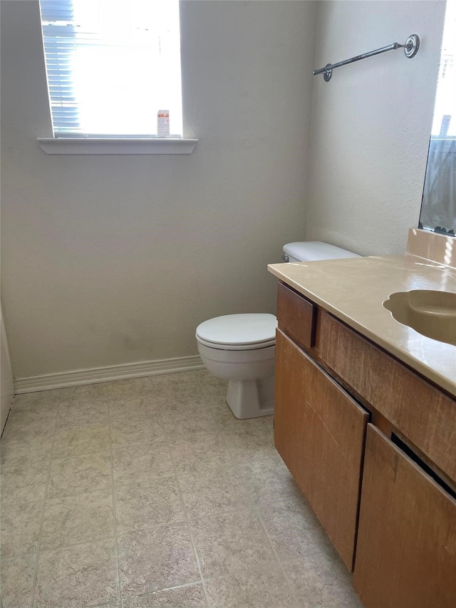 bathroom with baseboards, vanity, and toilet