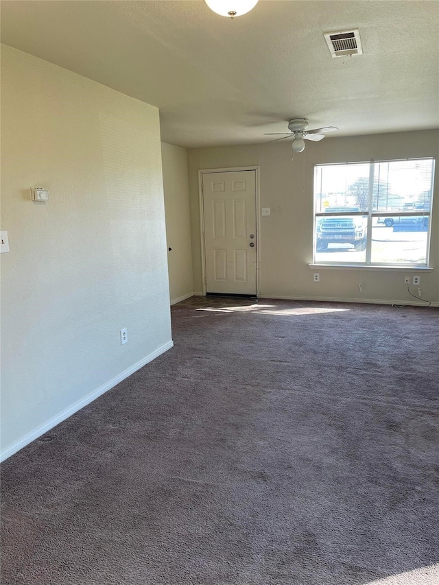 unfurnished room with visible vents, dark carpet, a ceiling fan, a textured ceiling, and baseboards