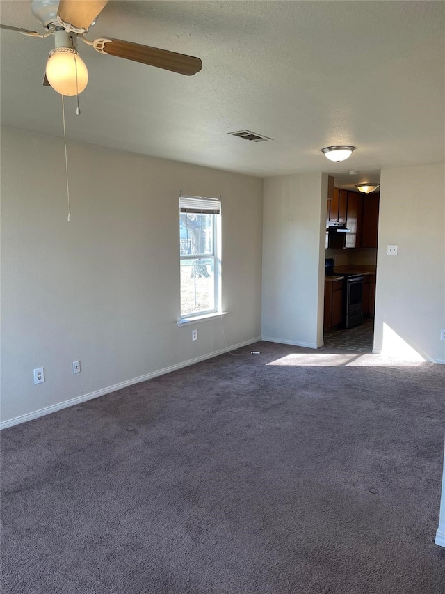 interior space featuring baseboards, visible vents, dark colored carpet, and a ceiling fan