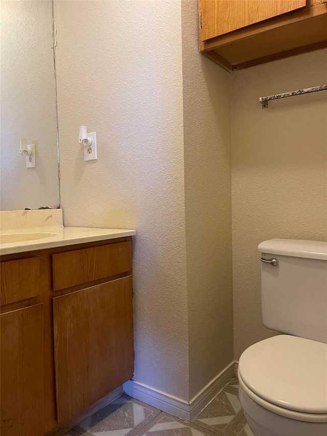 half bath featuring toilet, baseboards, and vanity