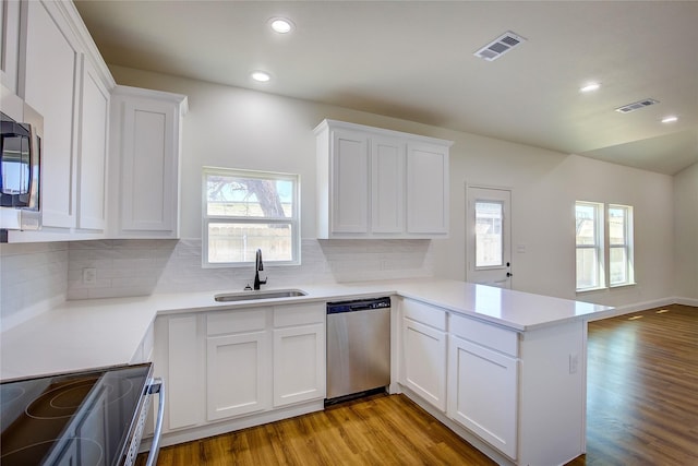 kitchen featuring a peninsula, white cabinetry, stainless steel appliances, and a sink