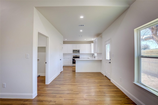 kitchen with light countertops, visible vents, appliances with stainless steel finishes, white cabinets, and a sink