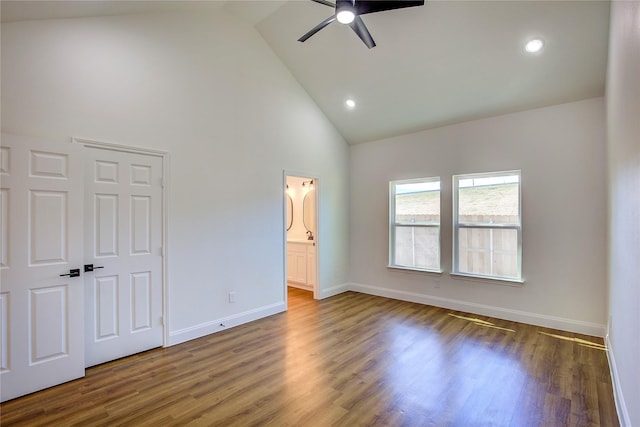 unfurnished bedroom with ceiling fan, high vaulted ceiling, dark wood-type flooring, baseboards, and ensuite bath