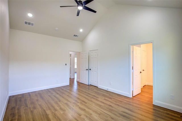 unfurnished bedroom featuring light wood finished floors, baseboards, visible vents, and high vaulted ceiling