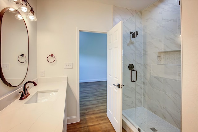 full bath with baseboards, a shower stall, vanity, and wood finished floors