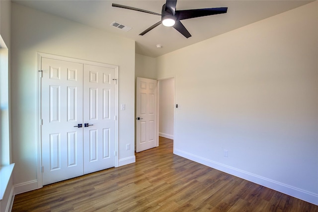 unfurnished bedroom featuring ceiling fan, wood finished floors, visible vents, baseboards, and a closet