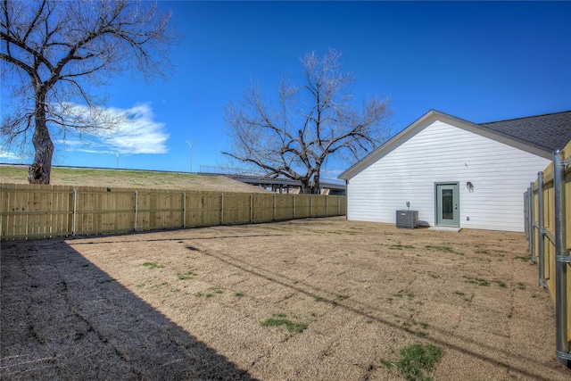 view of yard with a fenced backyard and central AC