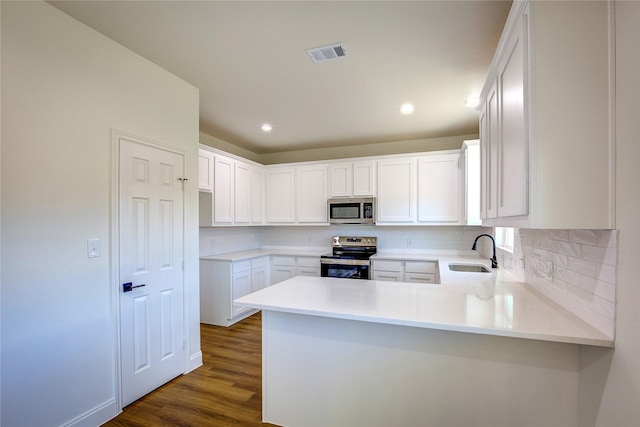 kitchen featuring visible vents, a peninsula, stainless steel appliances, light countertops, and white cabinetry