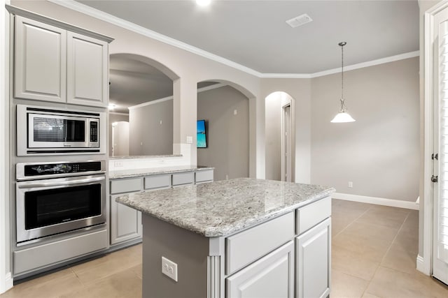 kitchen with light tile patterned floors, a kitchen island, visible vents, appliances with stainless steel finishes, and crown molding