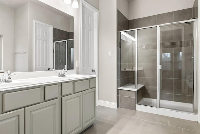 full bath with tile patterned floors, a sink, a shower stall, and double vanity