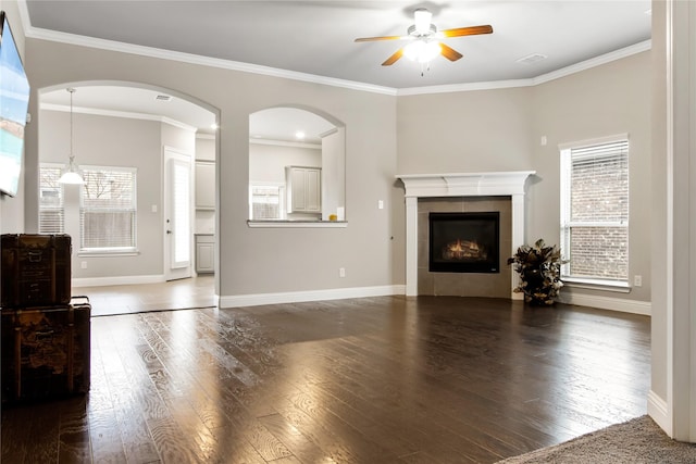 living area featuring dark wood-style floors, ornamental molding, a tiled fireplace, and baseboards