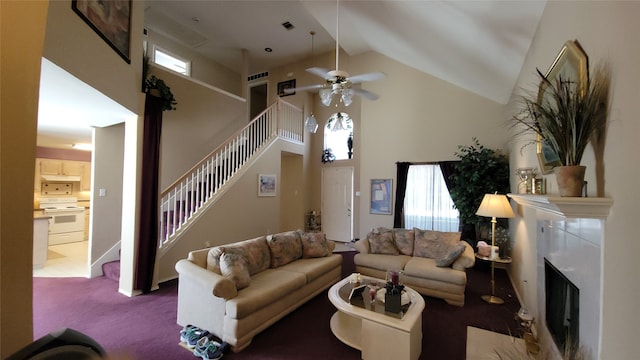 living area featuring a fireplace, visible vents, a towering ceiling, stairs, and carpet