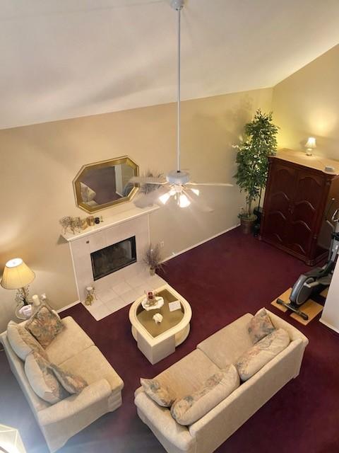 living room featuring vaulted ceiling, dark colored carpet, and a fireplace