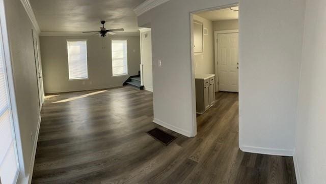 empty room featuring a ceiling fan, baseboards, ornamental molding, and dark wood-type flooring