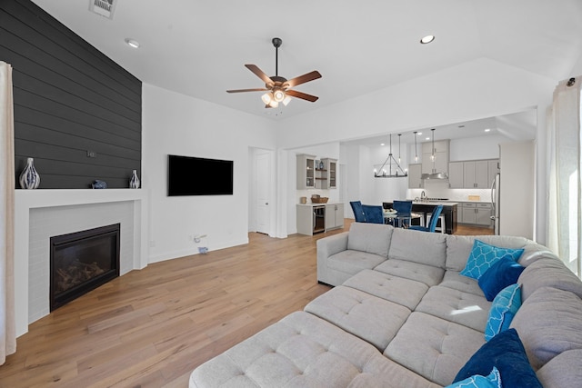 living area featuring recessed lighting, visible vents, a ceiling fan, light wood-type flooring, and a glass covered fireplace