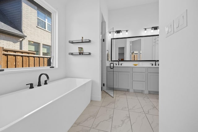 bathroom featuring a sink, marble finish floor, double vanity, and a freestanding bath