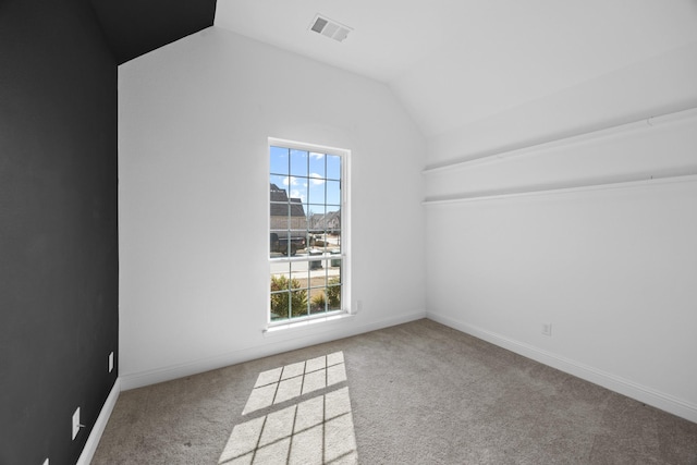 unfurnished room featuring light carpet, baseboards, visible vents, and vaulted ceiling