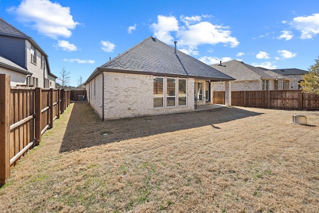 rear view of house with brick siding, a yard, a shingled roof, a residential view, and a fenced backyard