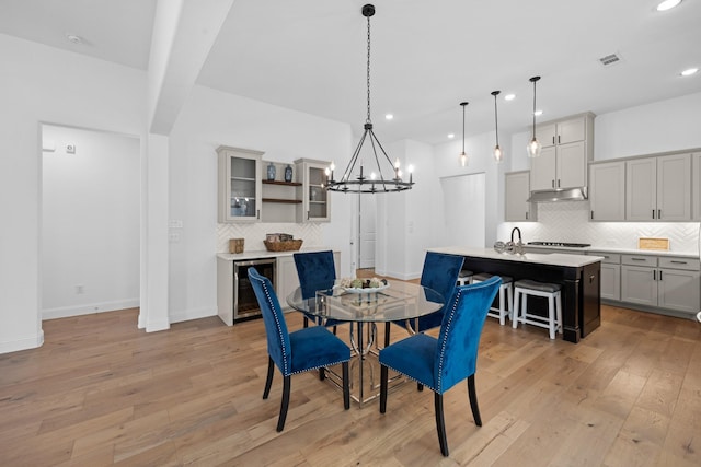 dining space with light wood-type flooring, beverage cooler, baseboards, and recessed lighting