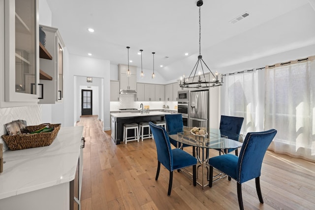 dining room featuring recessed lighting, a notable chandelier, visible vents, vaulted ceiling, and light wood-type flooring