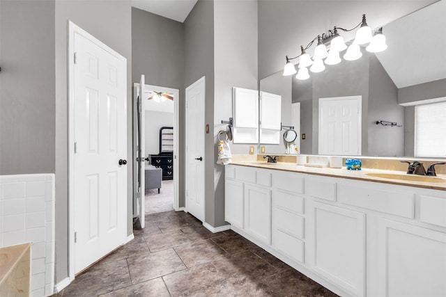 bathroom with double vanity, connected bathroom, a tub to relax in, and a sink