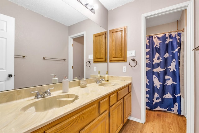 full bath featuring double vanity, a sink, and wood finished floors