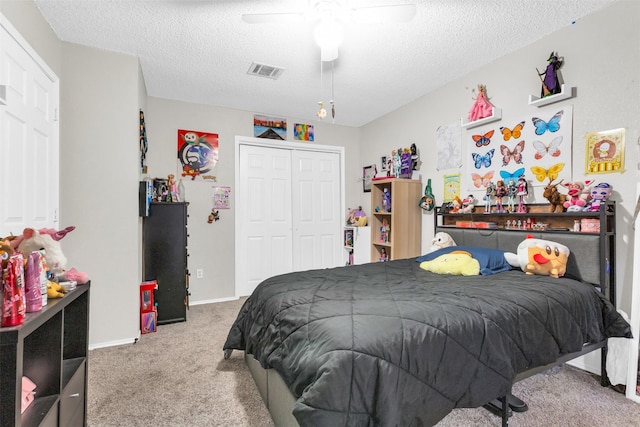 bedroom with ceiling fan, a textured ceiling, carpet floors, visible vents, and a closet