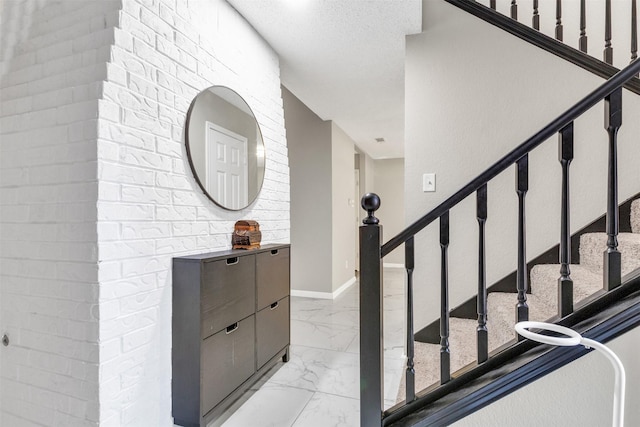 stairs with marble finish floor, baseboards, and a textured ceiling