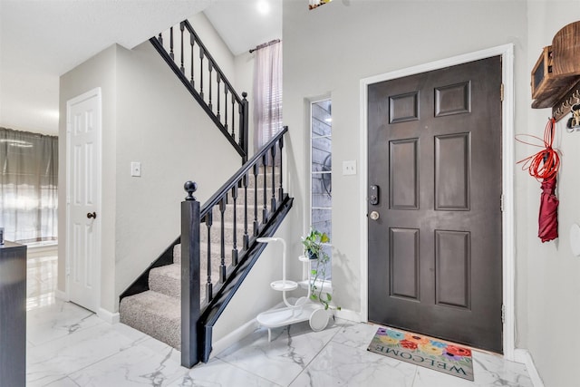 foyer featuring stairs, marble finish floor, a healthy amount of sunlight, and baseboards