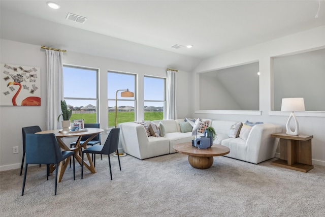 living area featuring lofted ceiling, visible vents, and light colored carpet