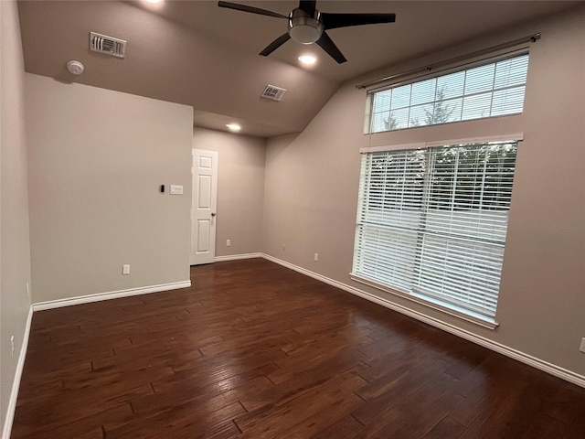 empty room featuring dark wood-style floors, lofted ceiling, baseboards, and a ceiling fan