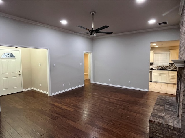 unfurnished living room featuring a sink, wood finished floors, visible vents, and crown molding